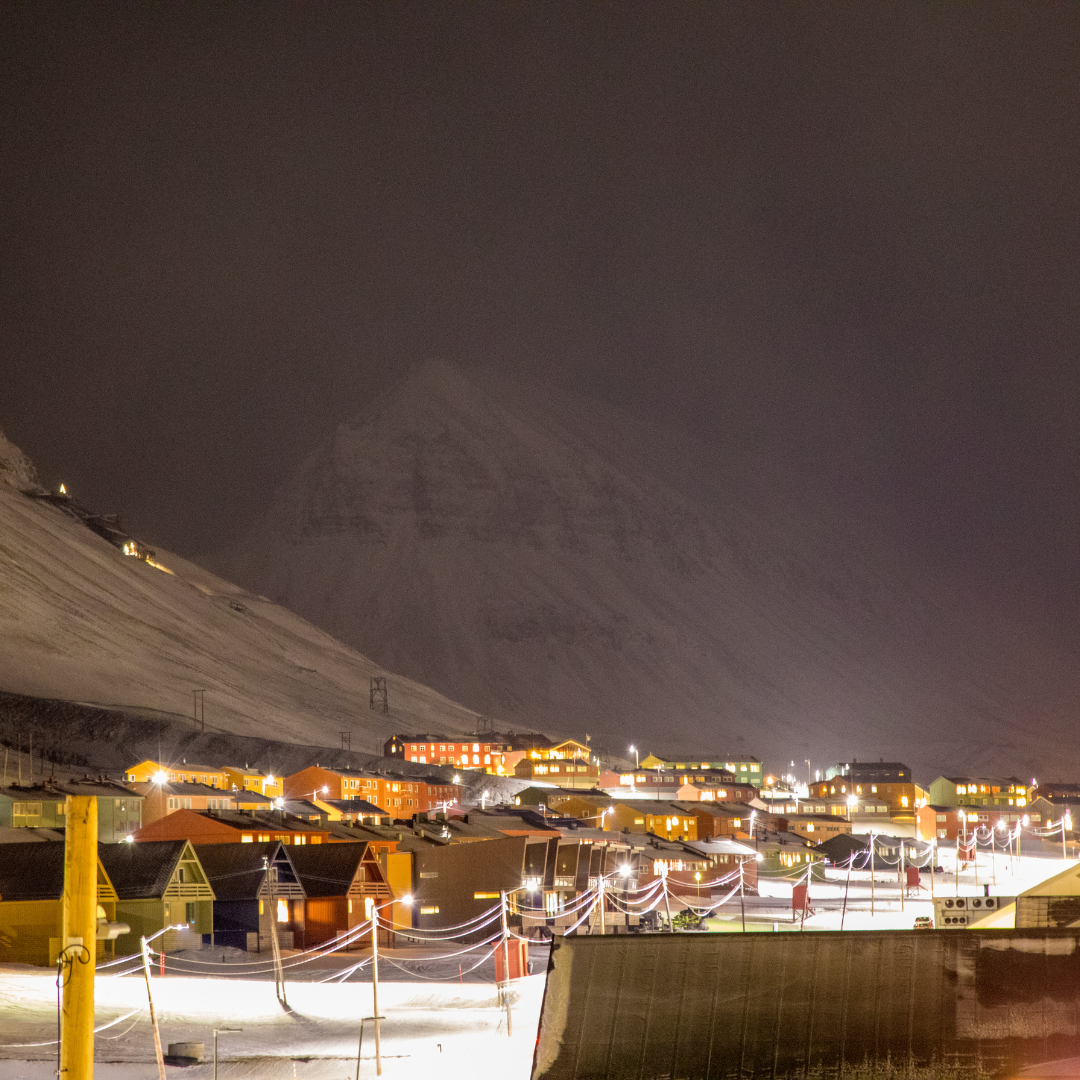 A snowy town at night with a yellow pole in the foreground