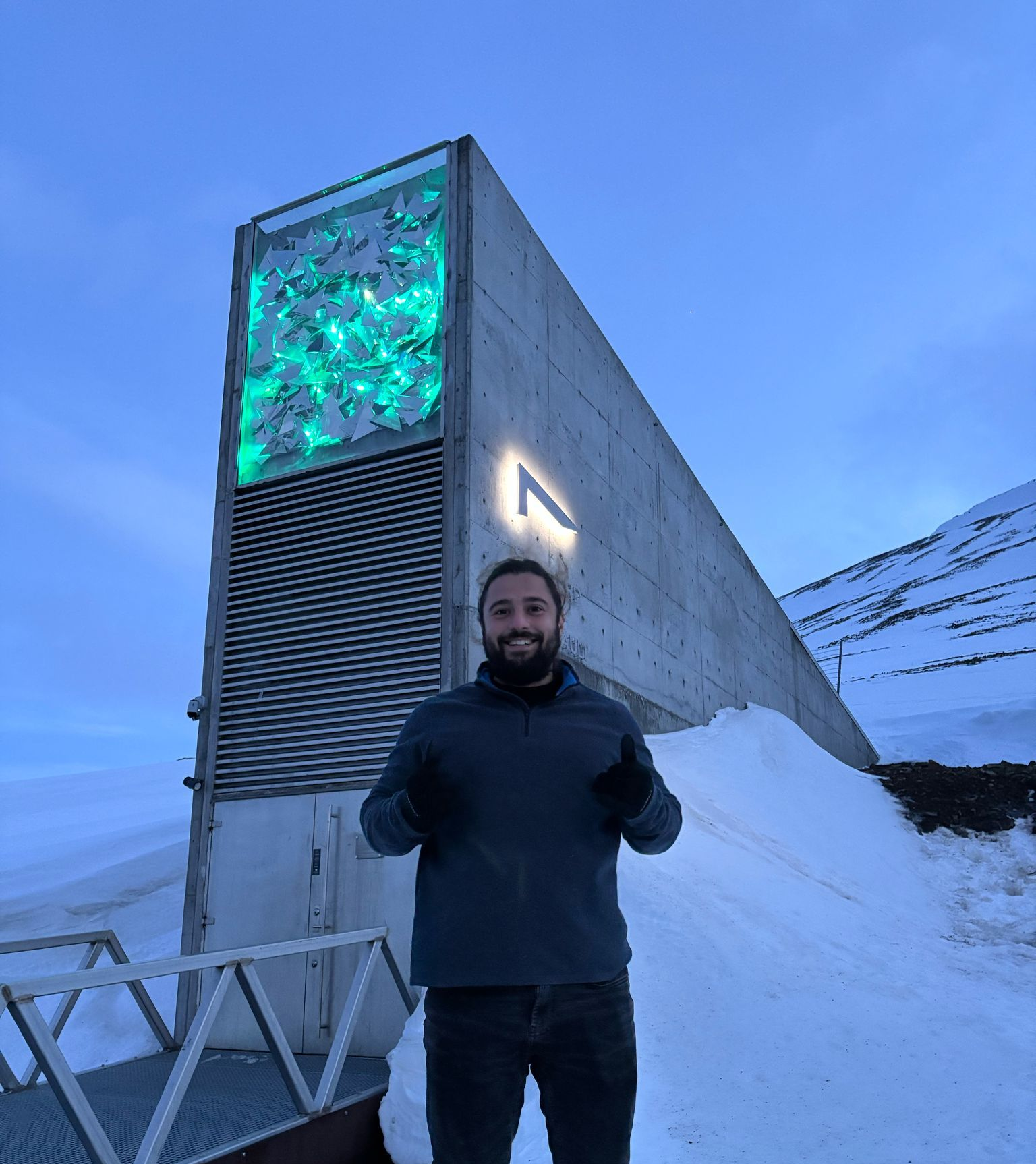 A man with a beard is smiling in front of a crowd of people.