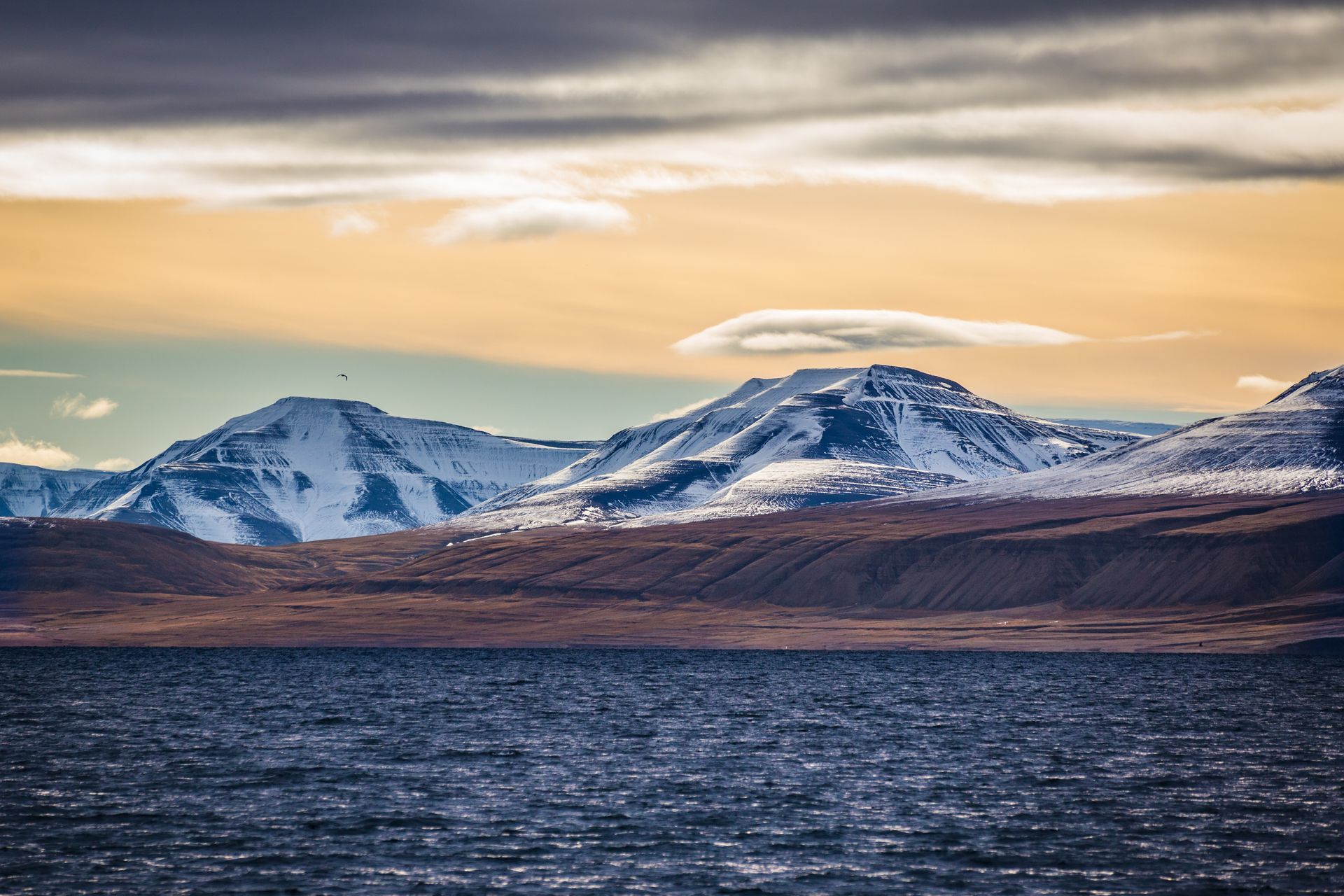 A lake with mountains in the background and a cloudy sky