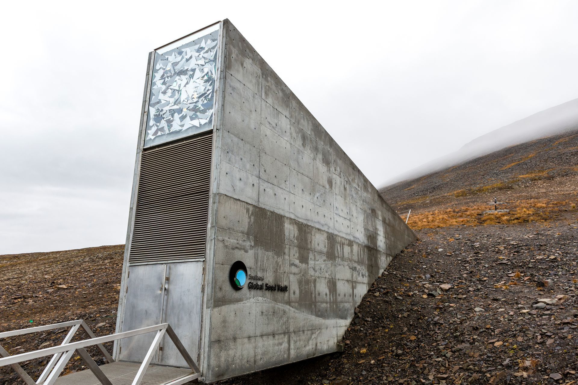 A large concrete building is sitting on top of a dirt hill.