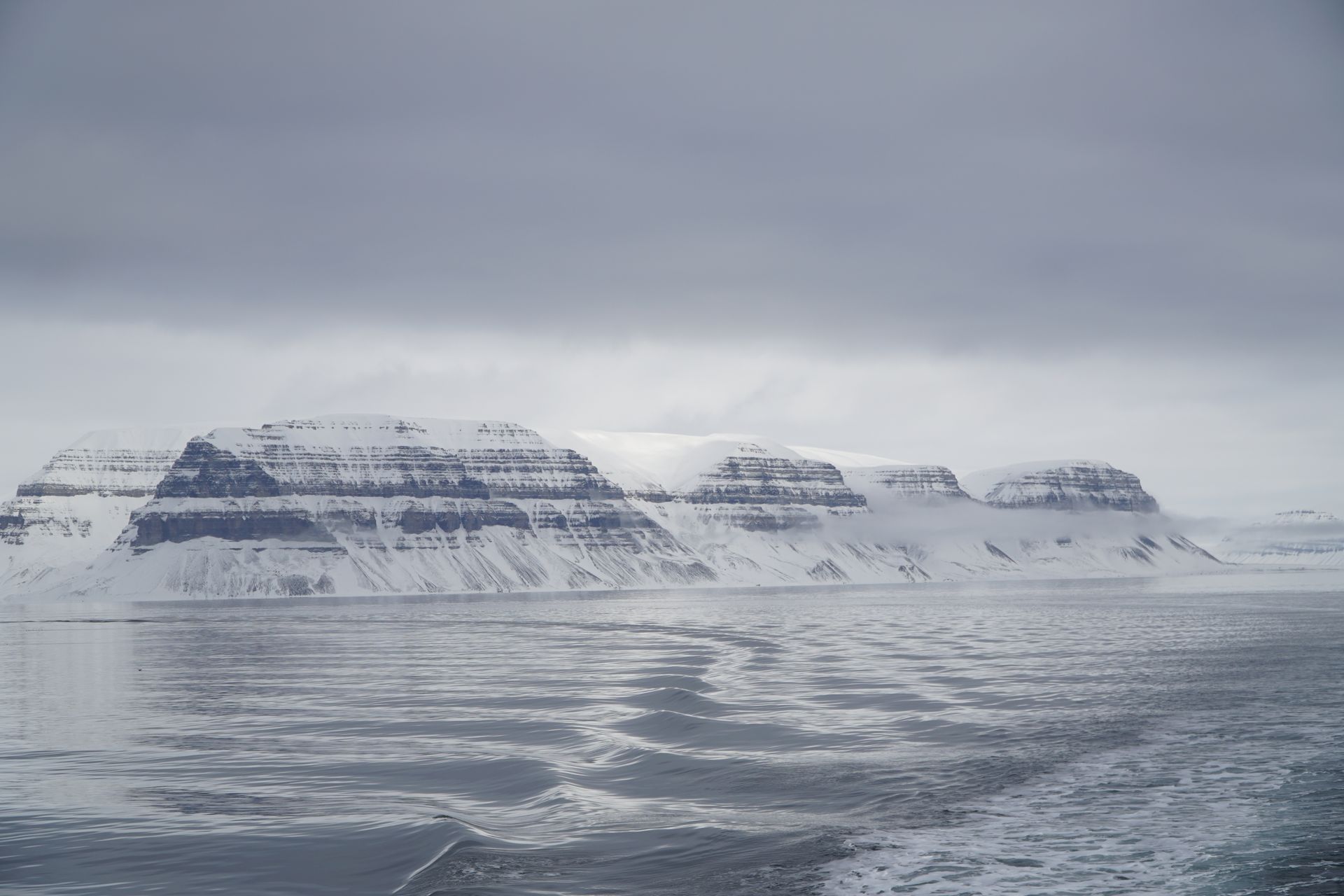 There is a mountain in the background and a body of water in the foreground.