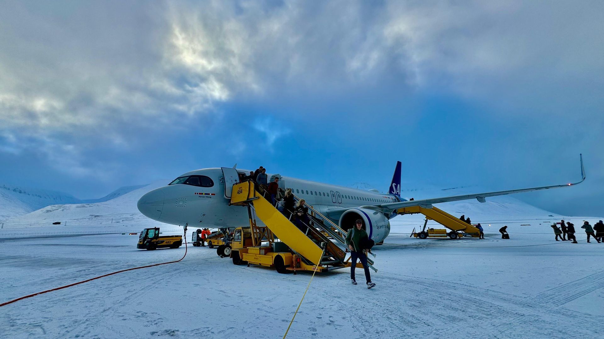 A group of people are boarding an airplane on a snowy runway.