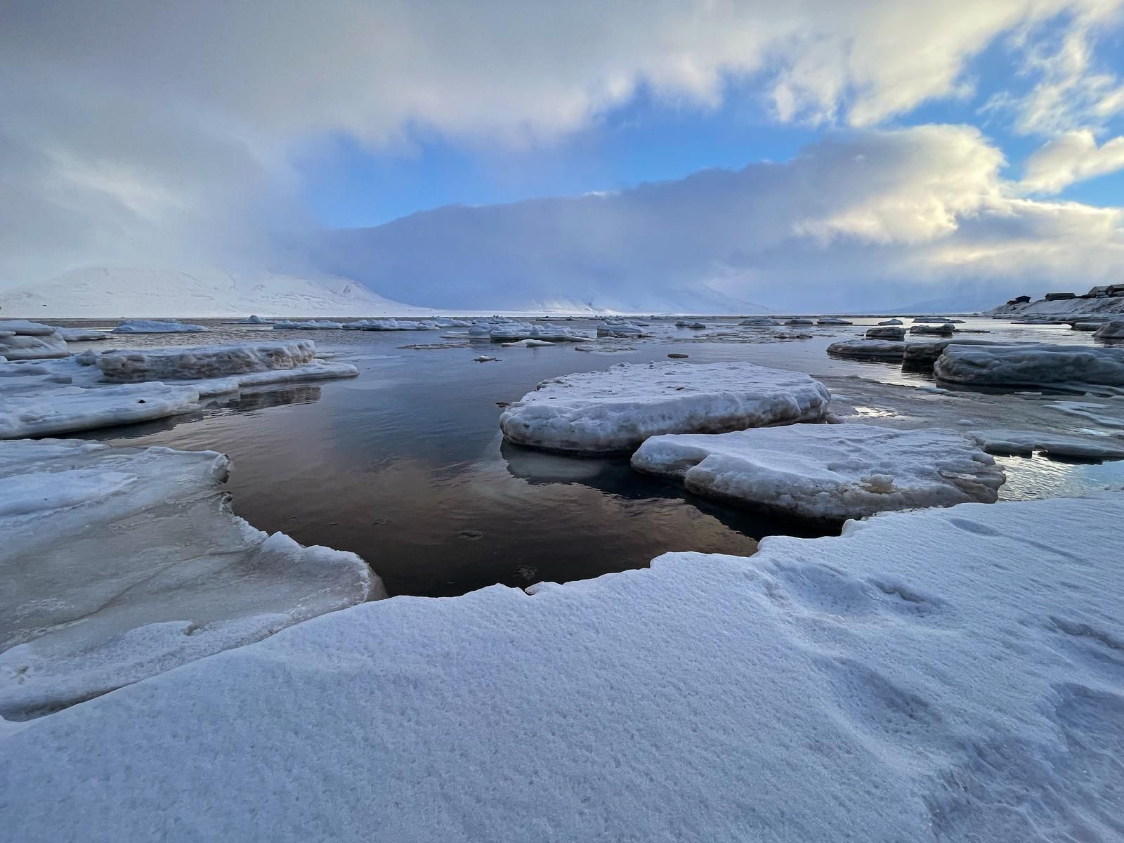 A large body of water surrounded by ice and snow.