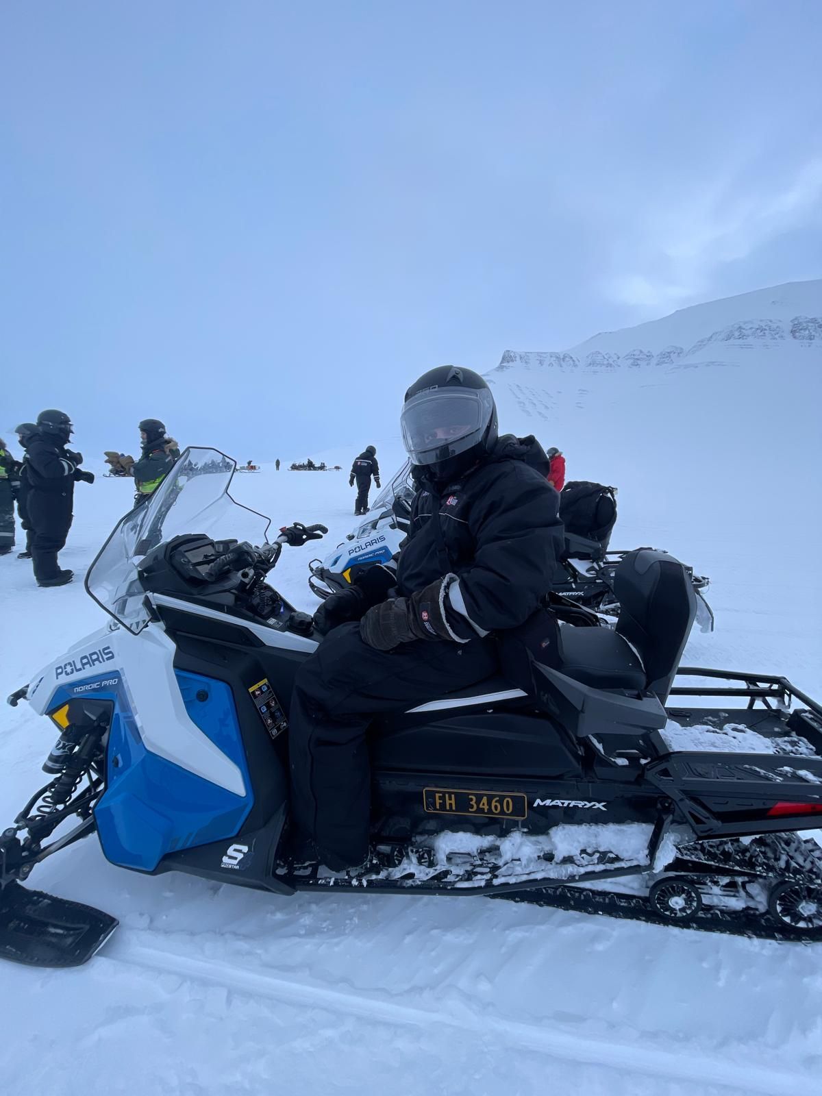 A man is riding a snowmobile under the aurora borealis