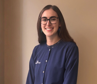 Couple hugging, smiling, mountain backdrop, overcast sky. Woman in sunglasses, man in jacket.