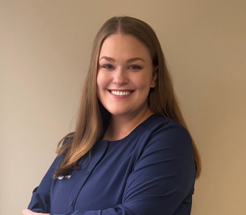 Woman in white lab coat smiles in a dental office.