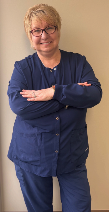 Pregnant woman in pink dress with older woman at a baby shower with floral backdrop, smiling.