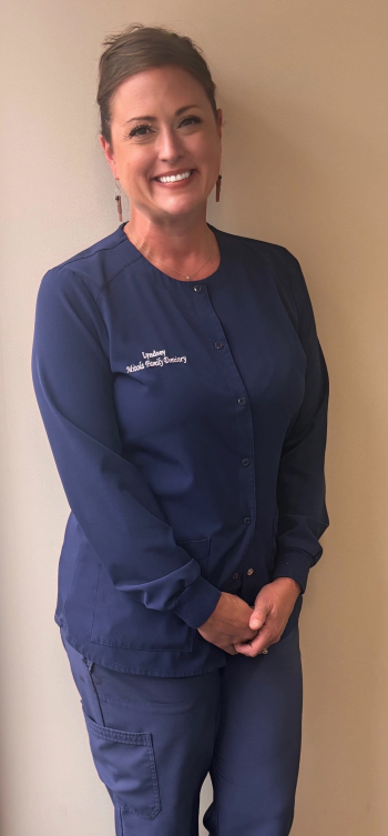 Family portrait: Smiling people, woman, man, and two young girls against gray background.
