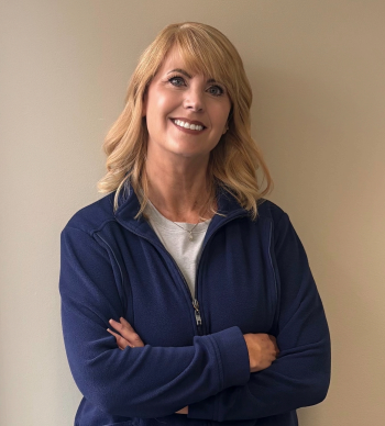 Family posing at a theme park, some wearing red shirts and mouse ears; greenery backdrop.