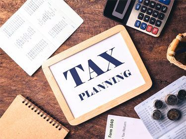 Tax planning sign with calculator, coins, and financial documents on a wooden desk.
