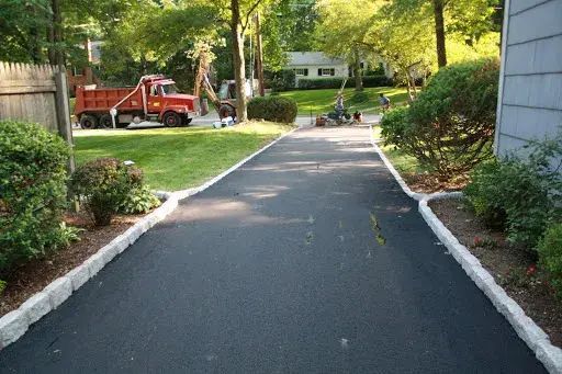 Yellow curb separating asphalt and sidewalk by a building.