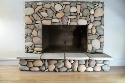 Fireplace with a stone facade against a white wall and light wood floor.