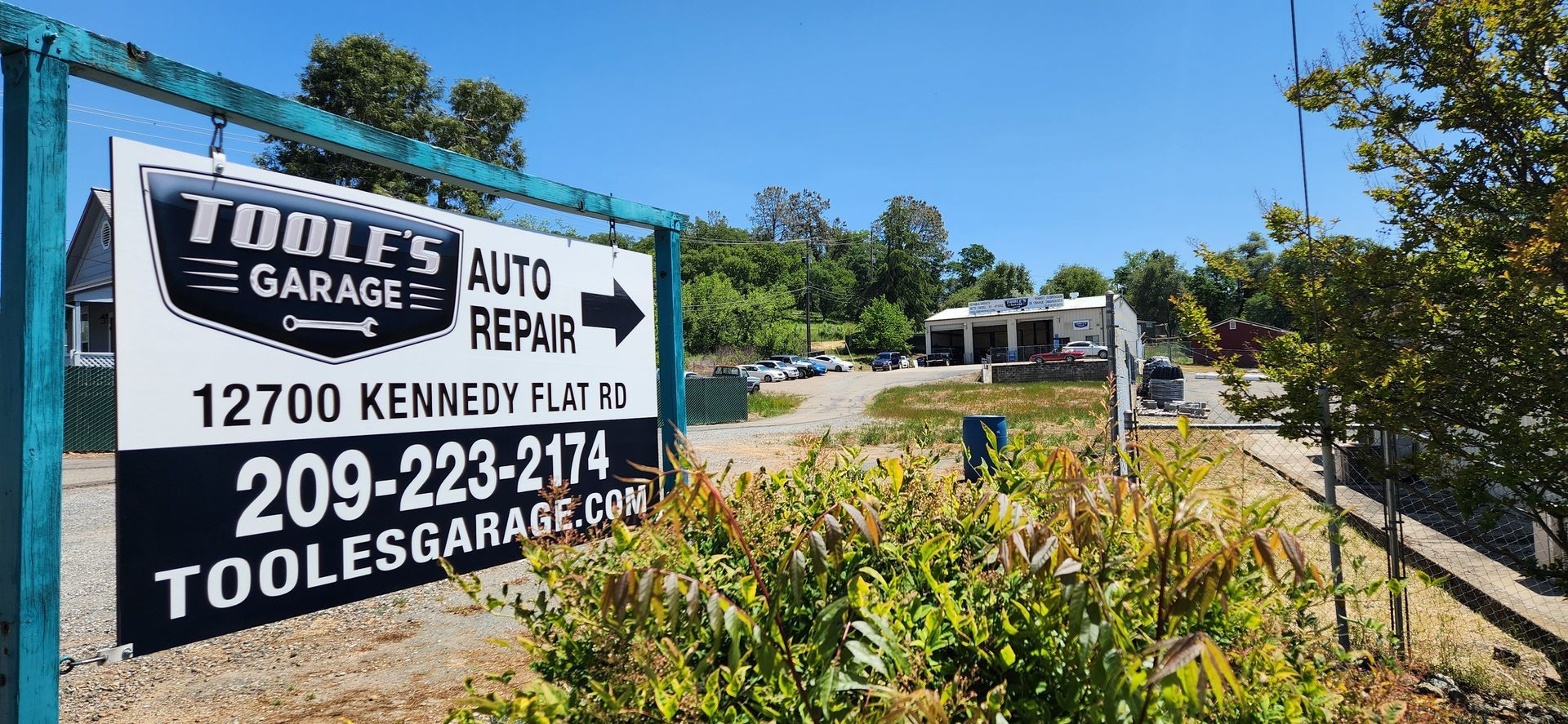 A sign for tools garage auto repair is hanging on a fence.