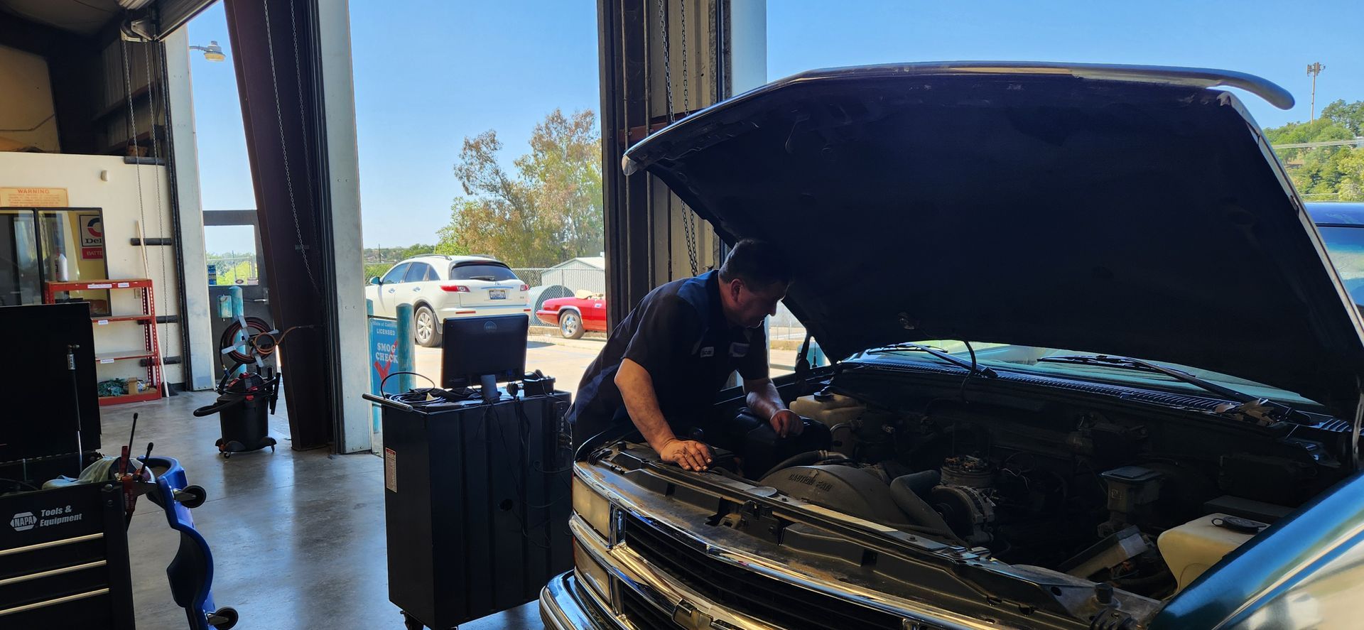 A man is working on the engine of a truck in a garage.
