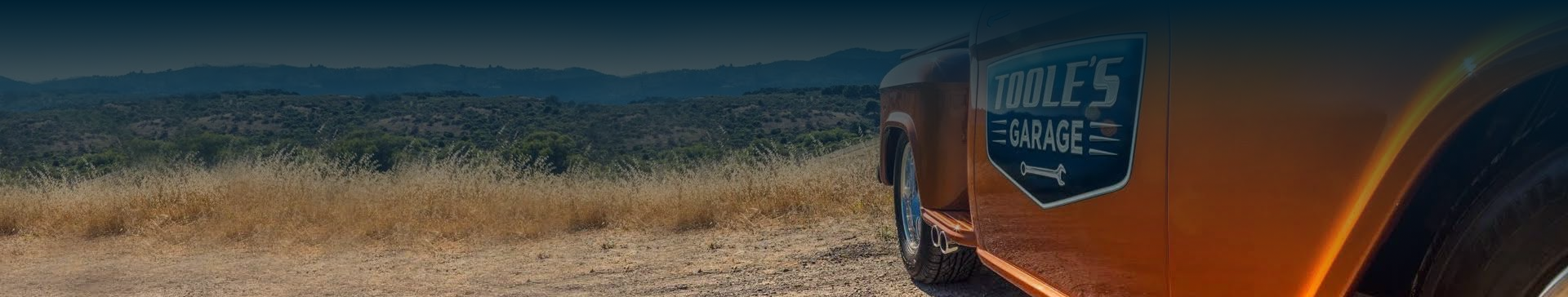 A close up of a car driving down a dirt road.