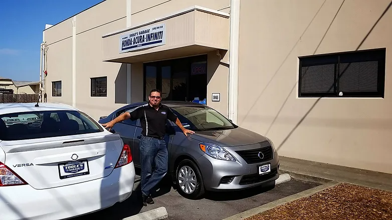 A man standing next to two cars in front of a building