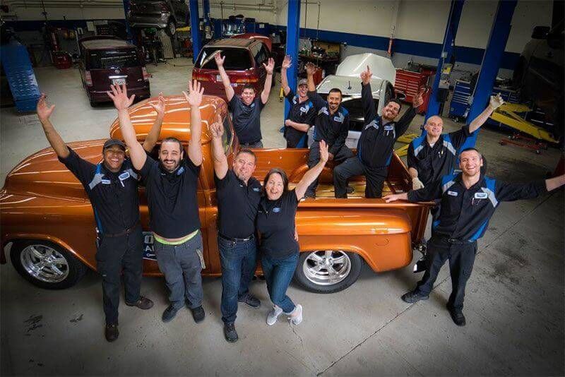 A group of people are posing for a picture in front of an orange truck.
