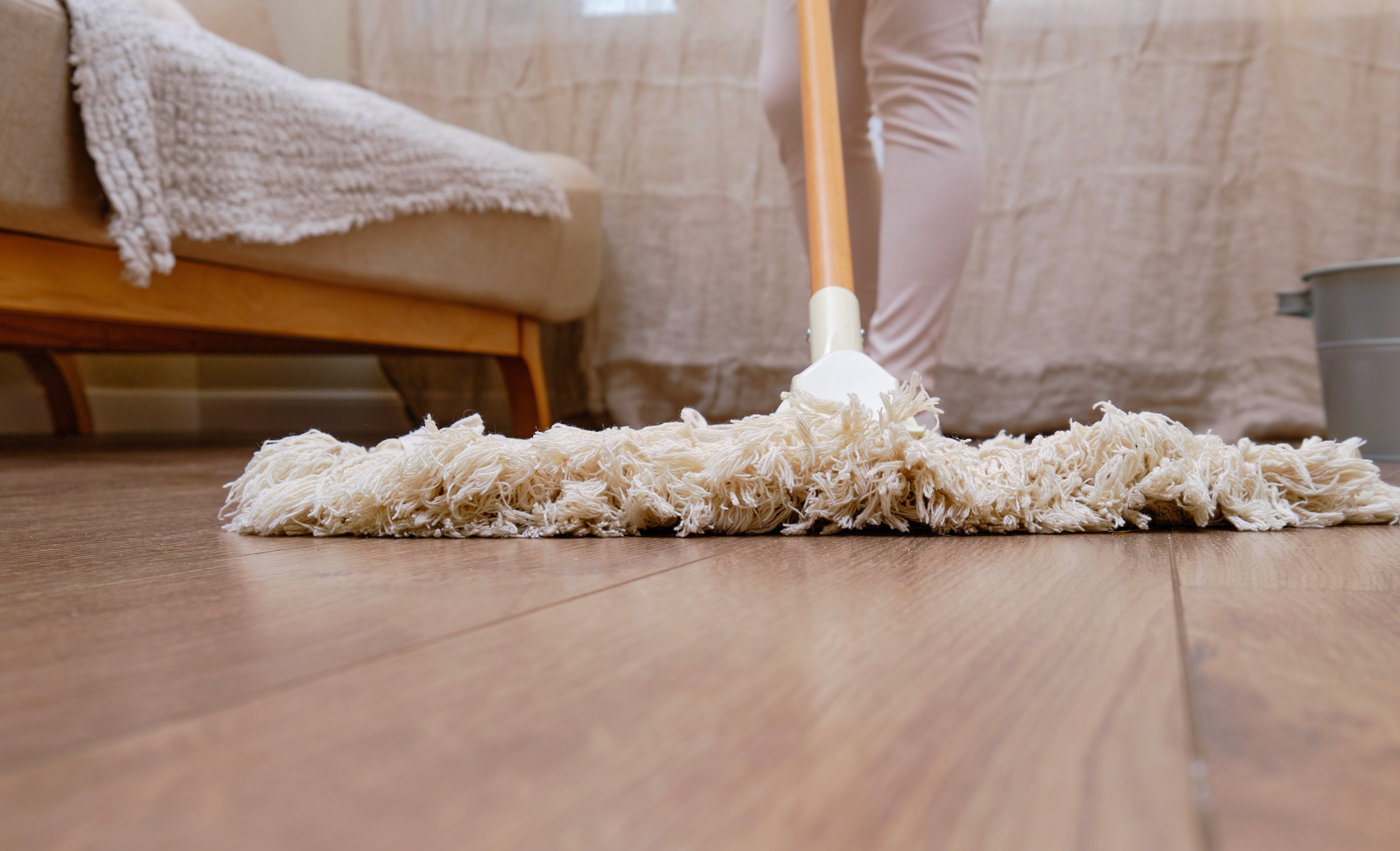 A person is mopping the floor in a living room.