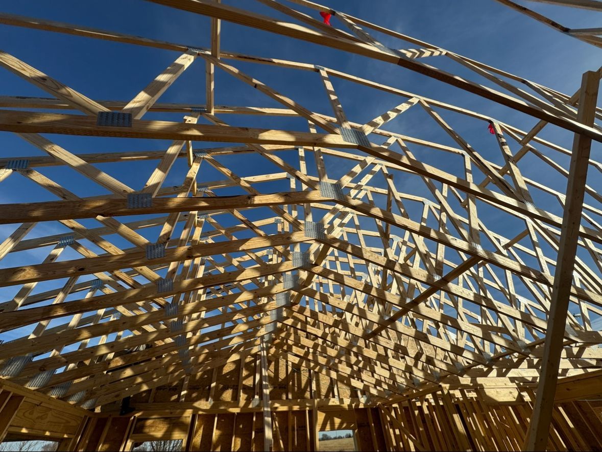 Wooden roof trusses under construction against a blue sky, viewed from below
