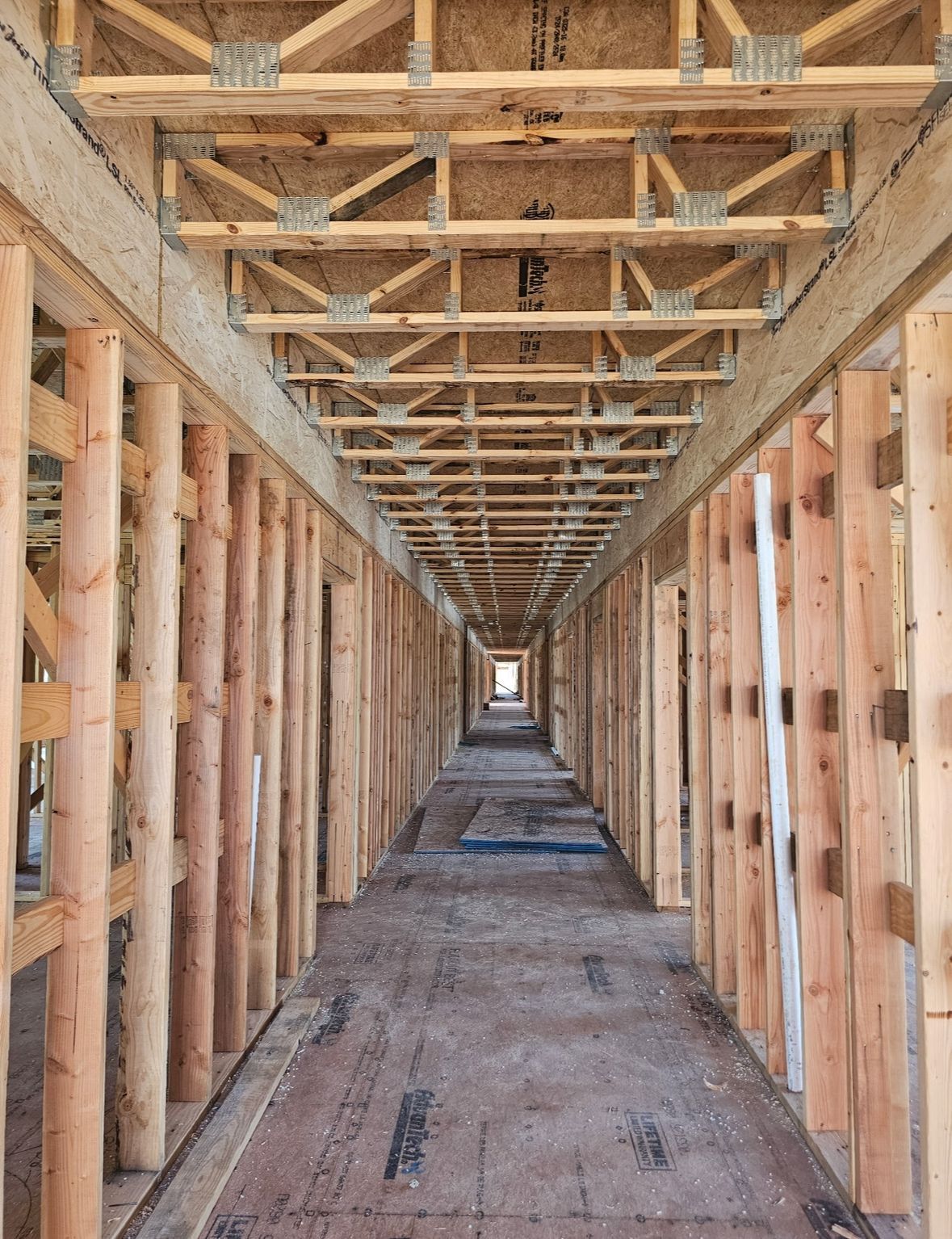 Wood-framed hallway under construction, with exposed beams and a long, narrow corridor.