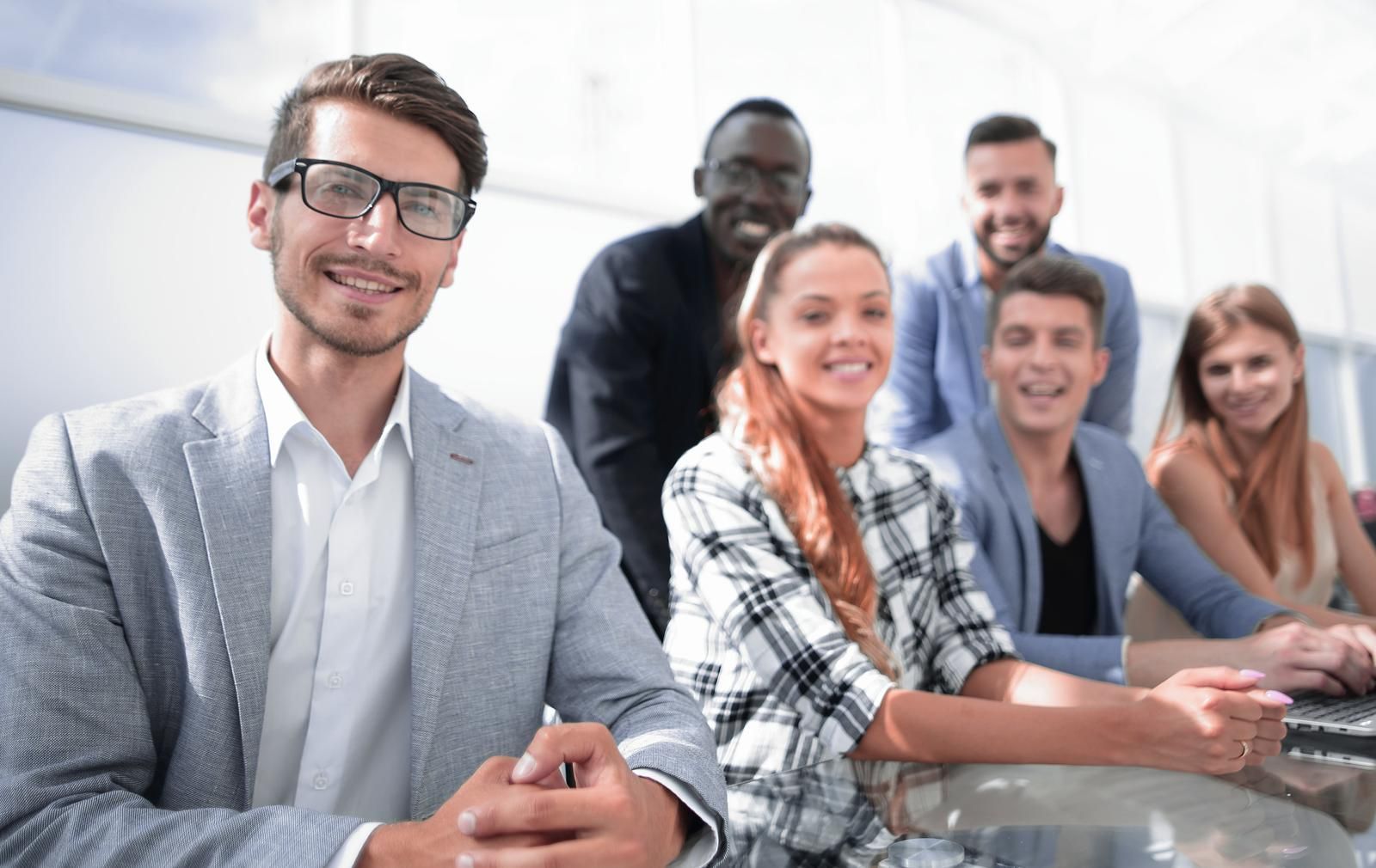 A group of people are sitting around a table and smiling.