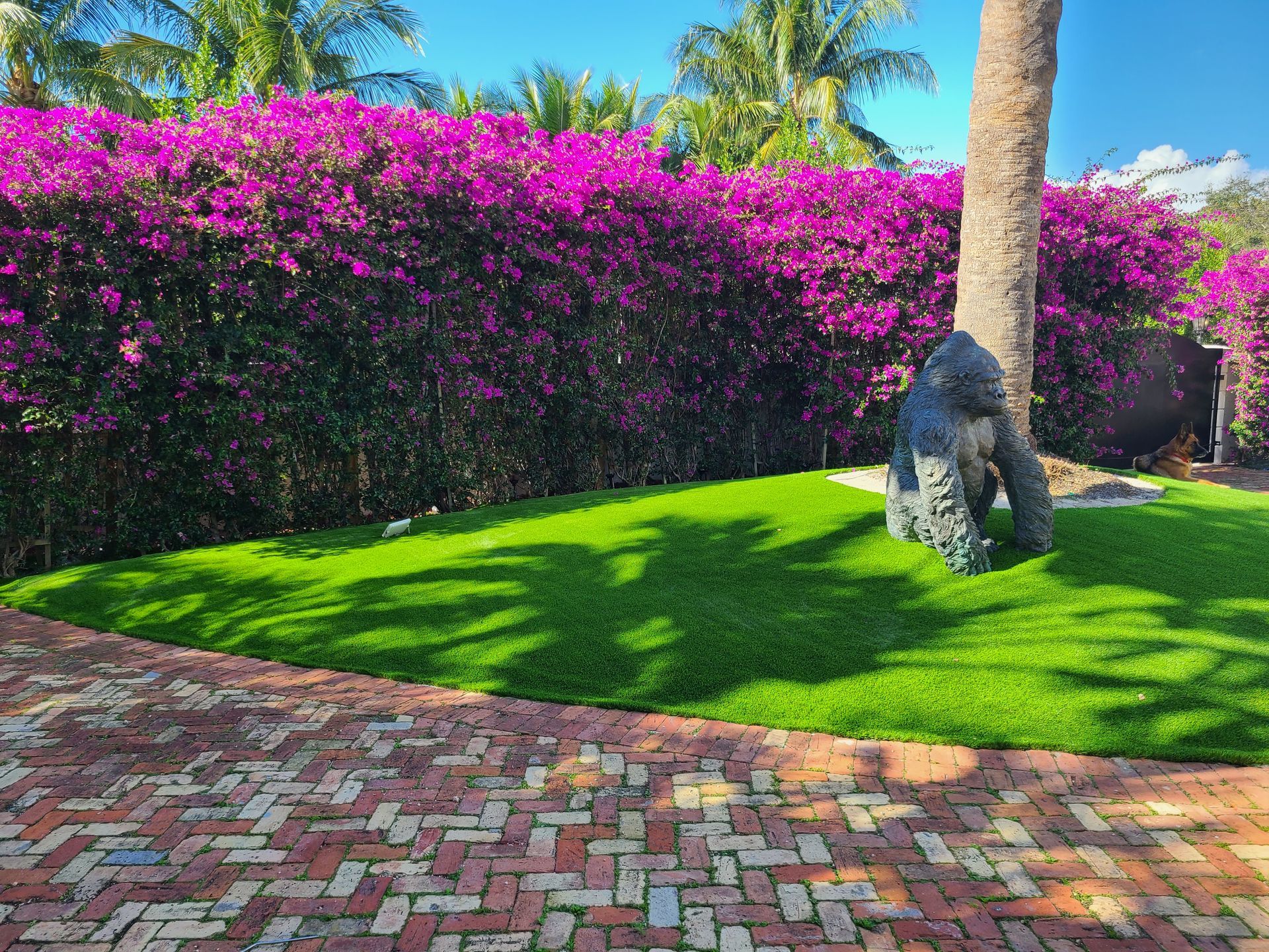 A statue of a gorilla sitting on top of a lush green lawn.