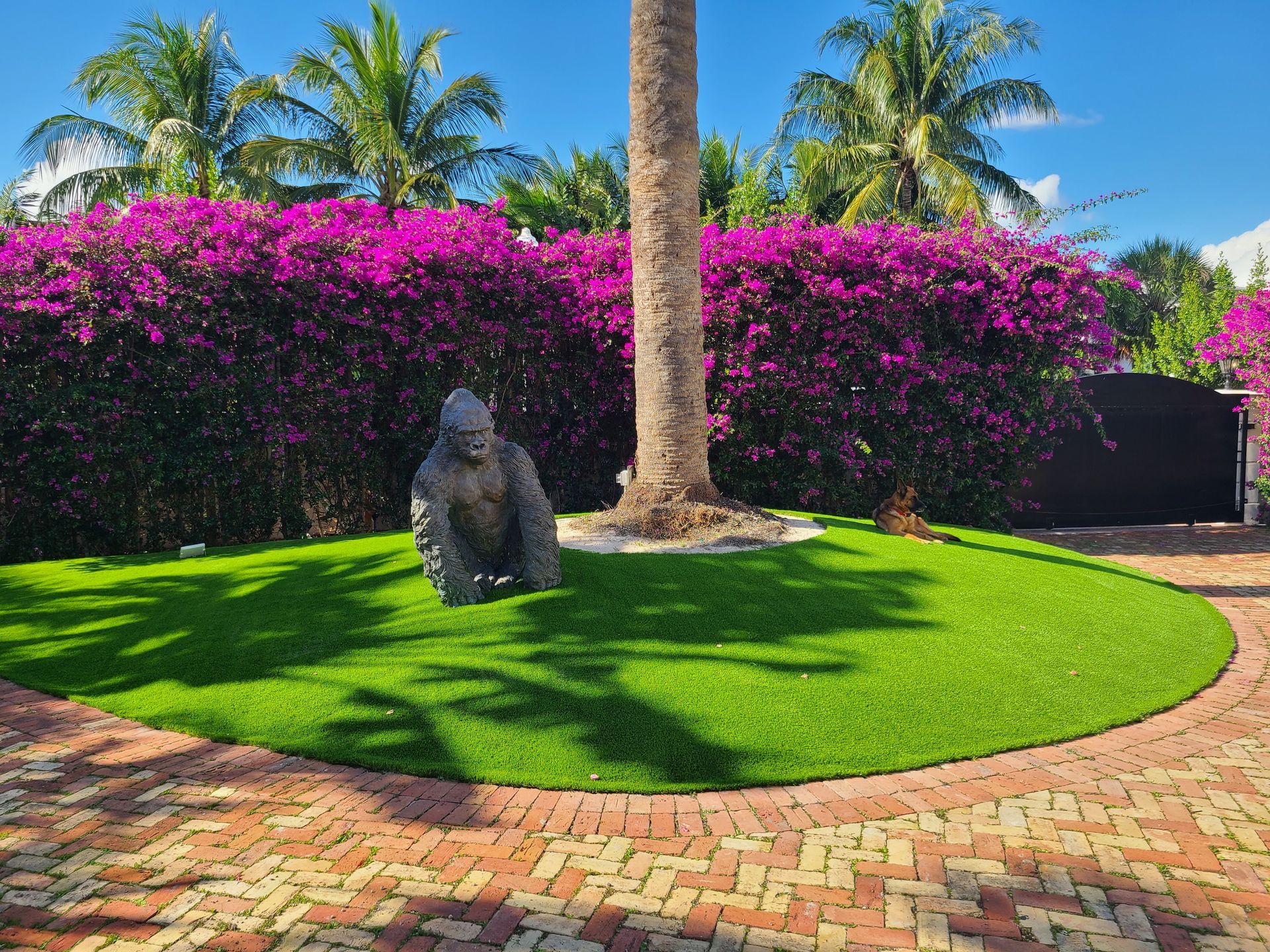 A statue of a gorilla is sitting in the middle of a lush green lawn.