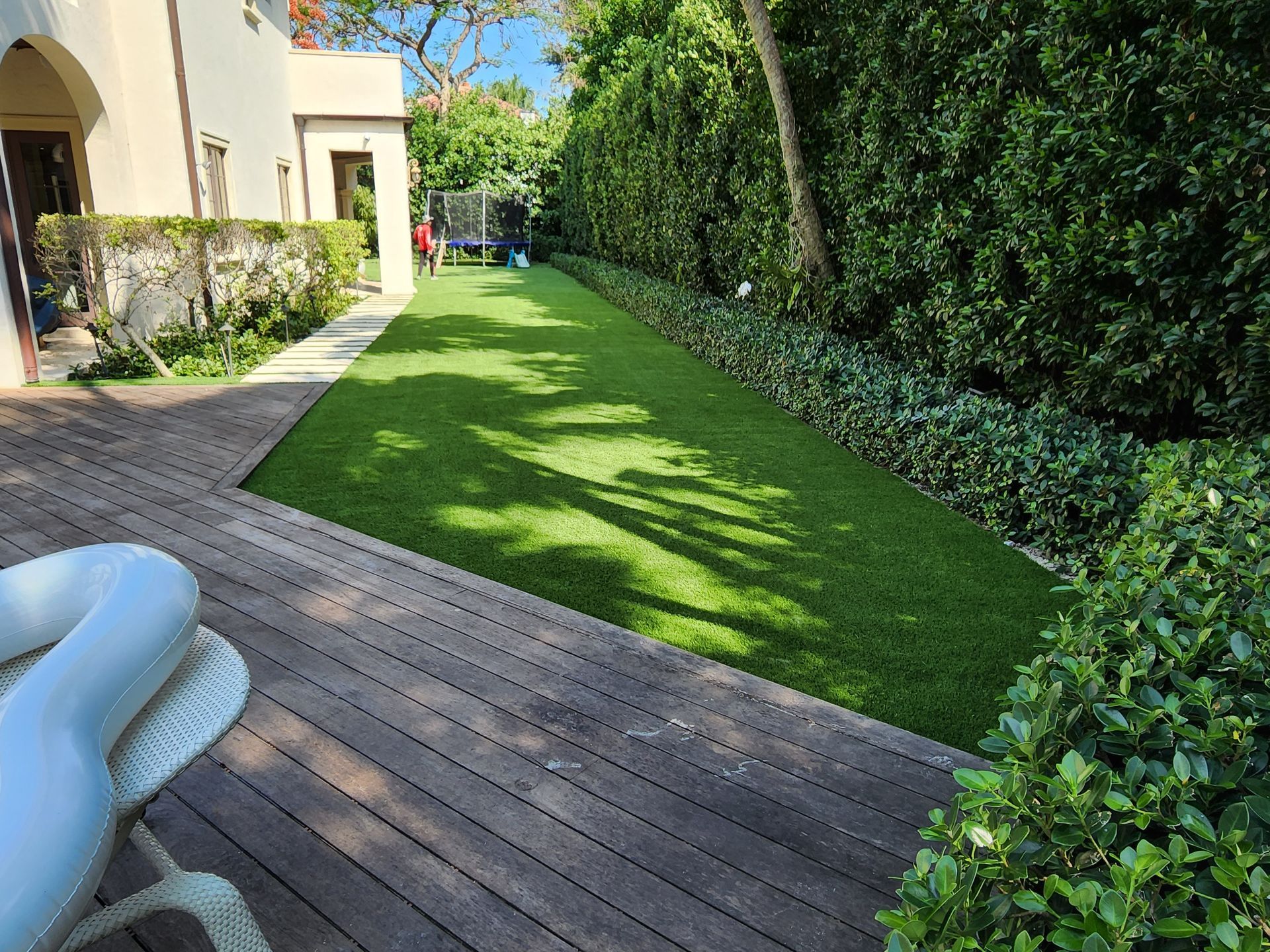 A wooden deck with a chair and a lawn in front of a house.
