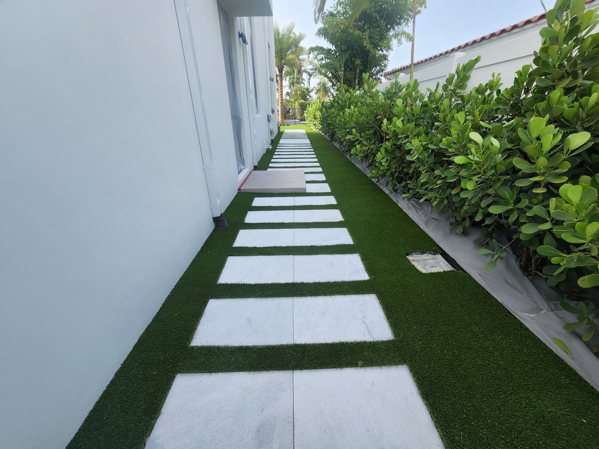 A walkway with grass and white steps leading to a house