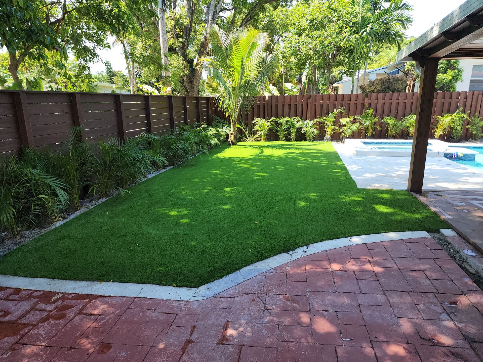 A backyard with a brick walkway and a swimming pool.
