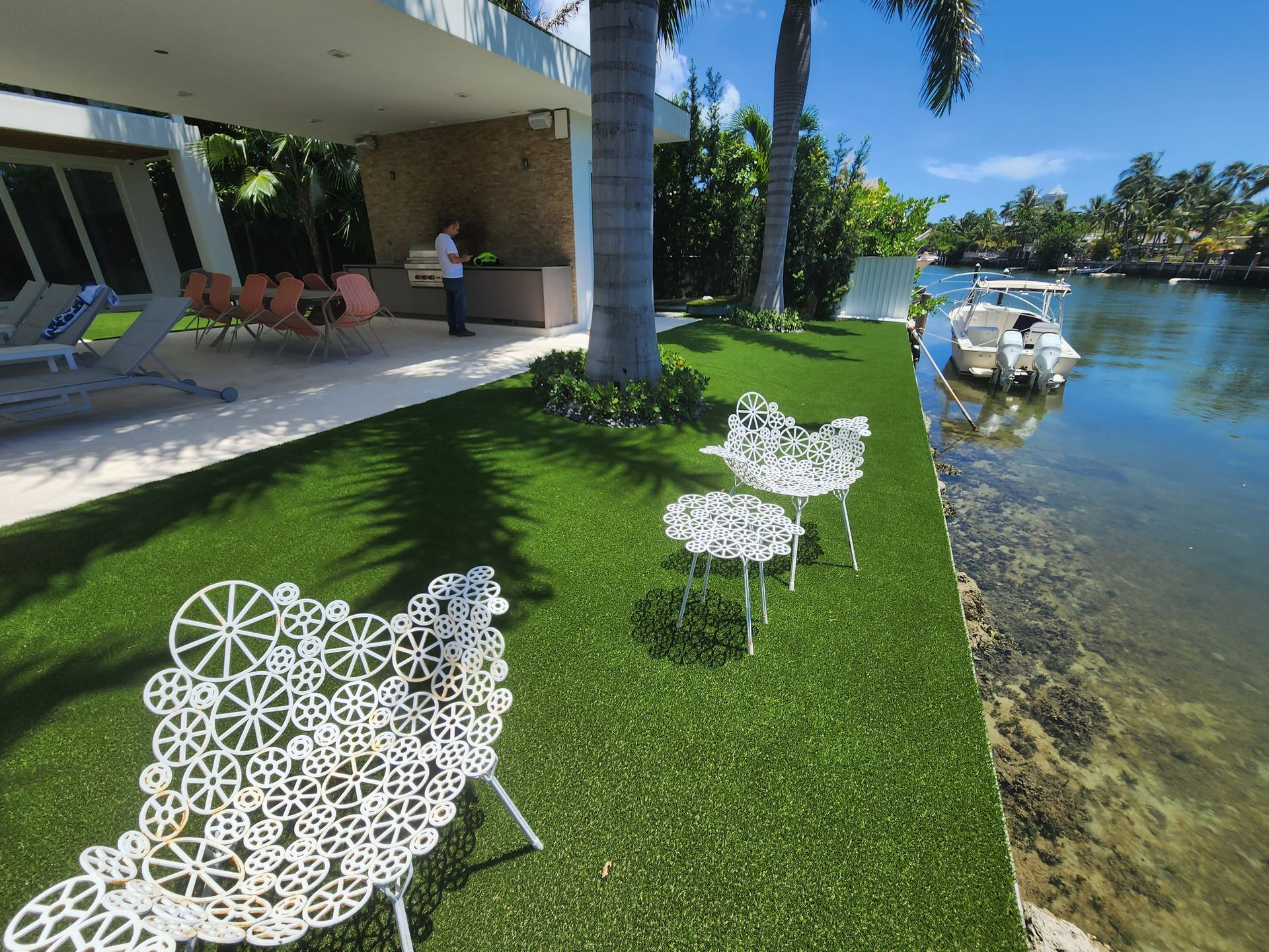A white boat is docked in the water near a house