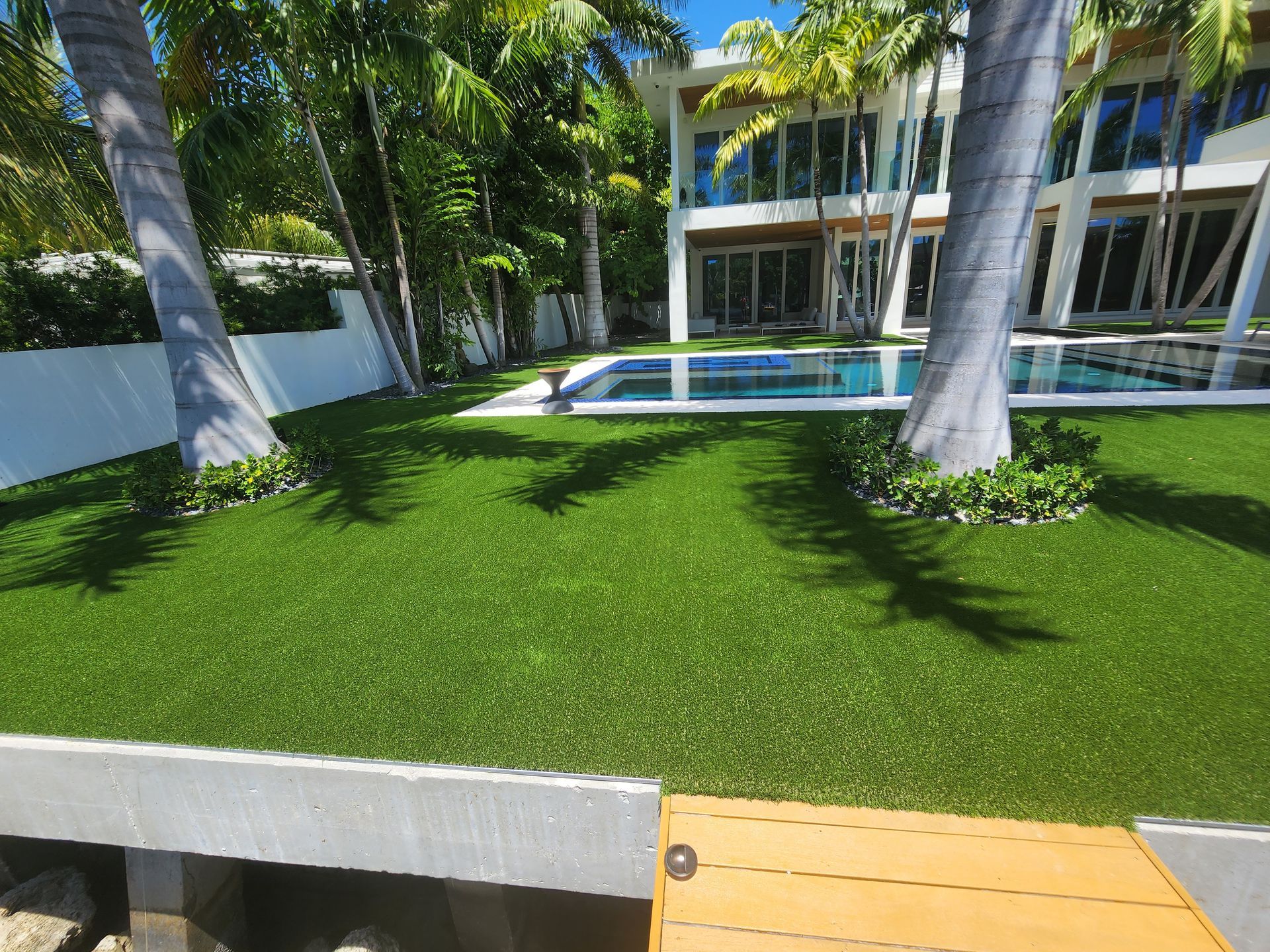 A large house with a swimming pool and a lush green lawn in front of it.