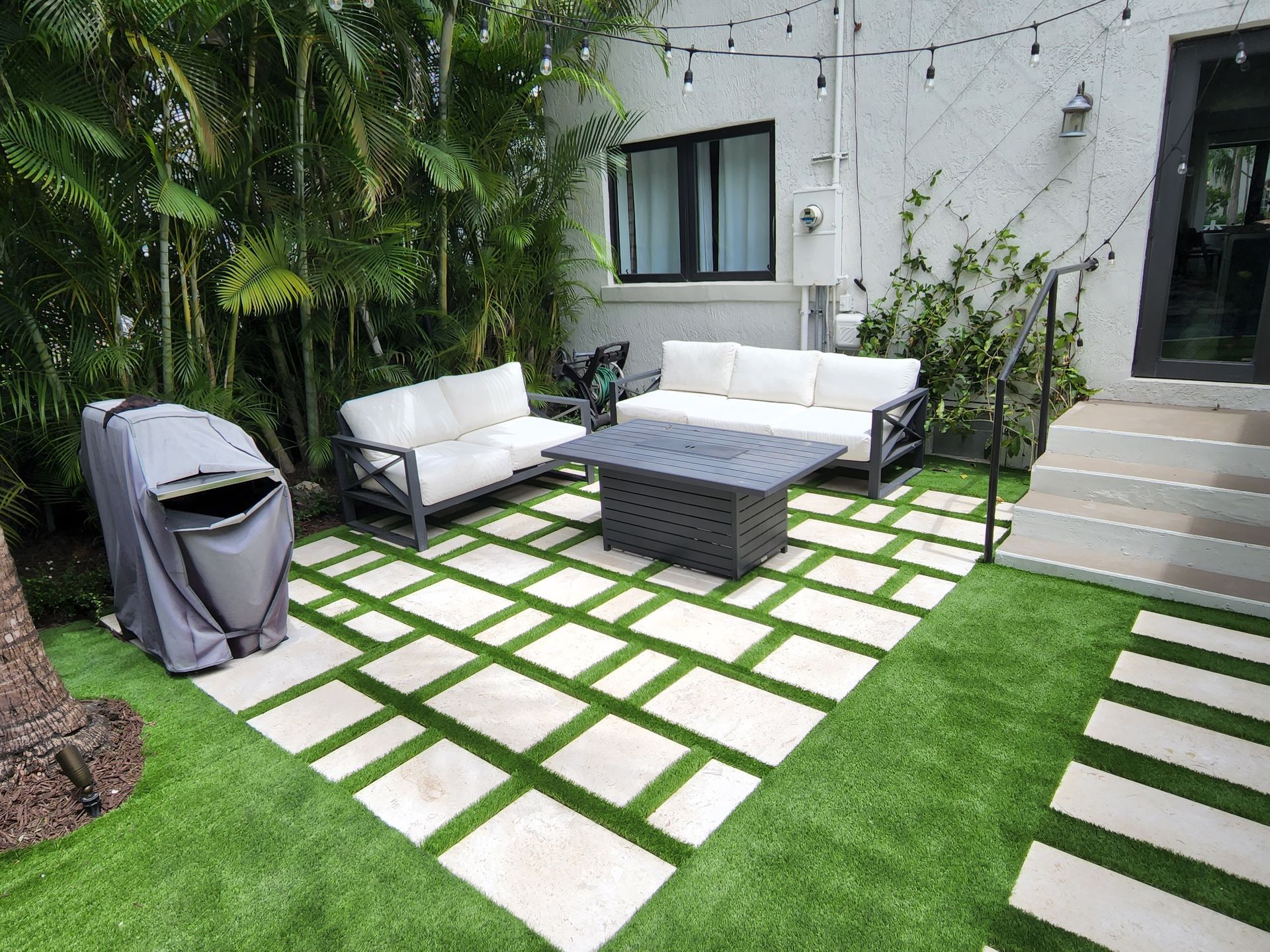 There is a patio with a couch , table , and grill.