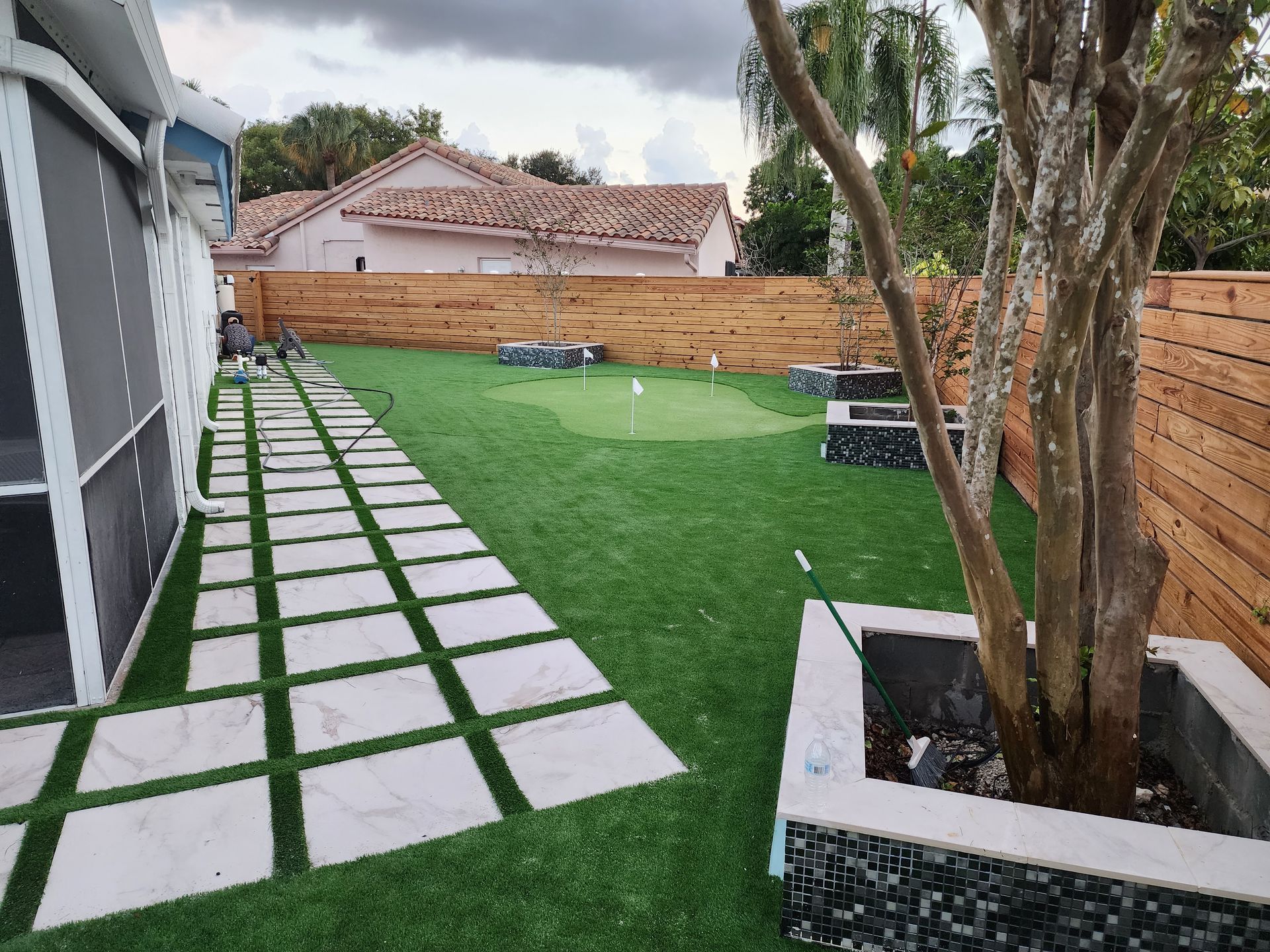 There is a putting green in the backyard of a house.