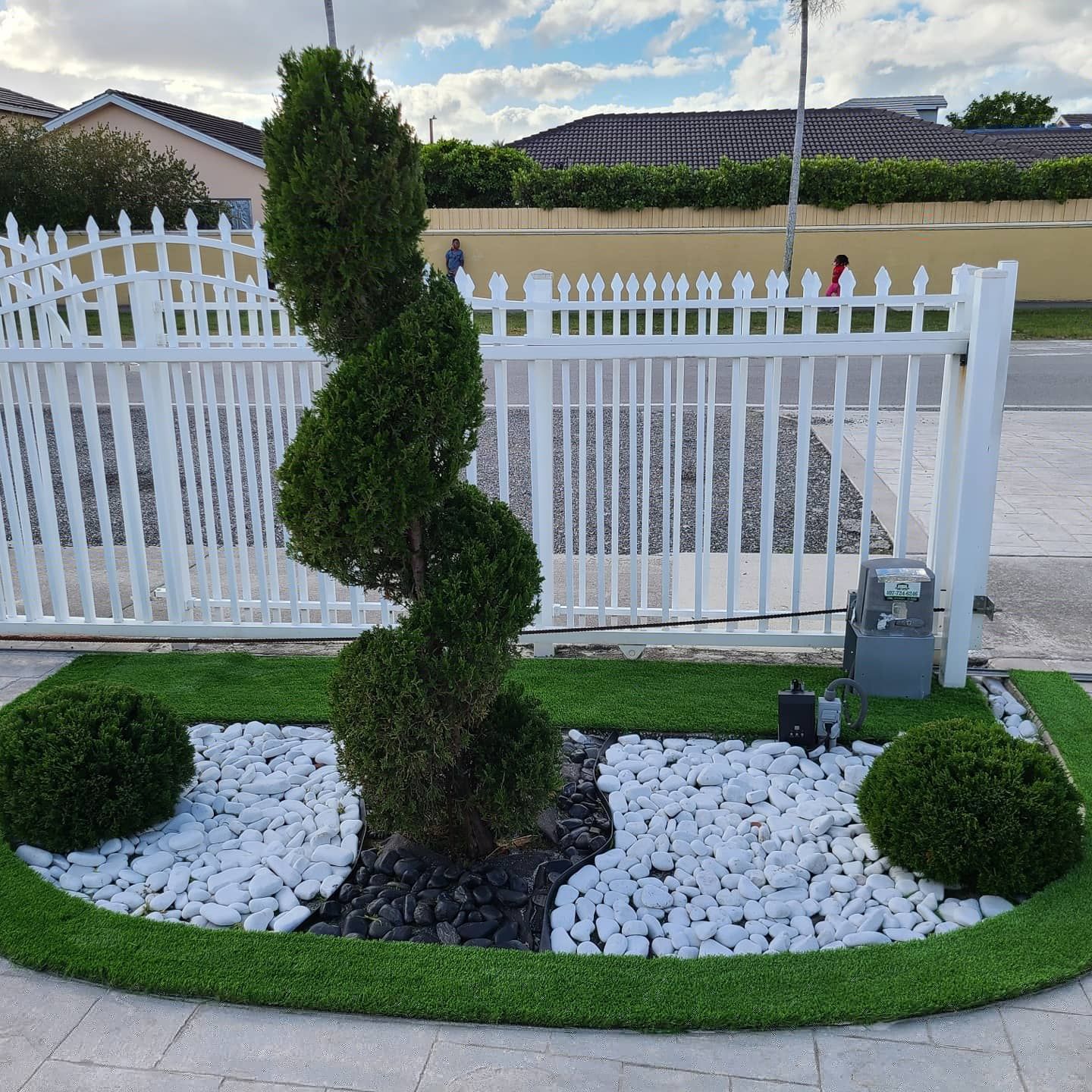 A white picket fence with a spiral tree in the middle