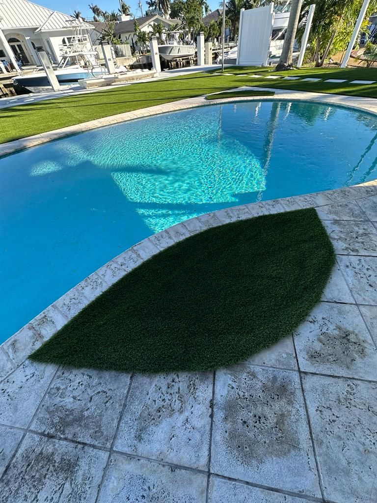 A leaf shaped rug is sitting next to a swimming pool.