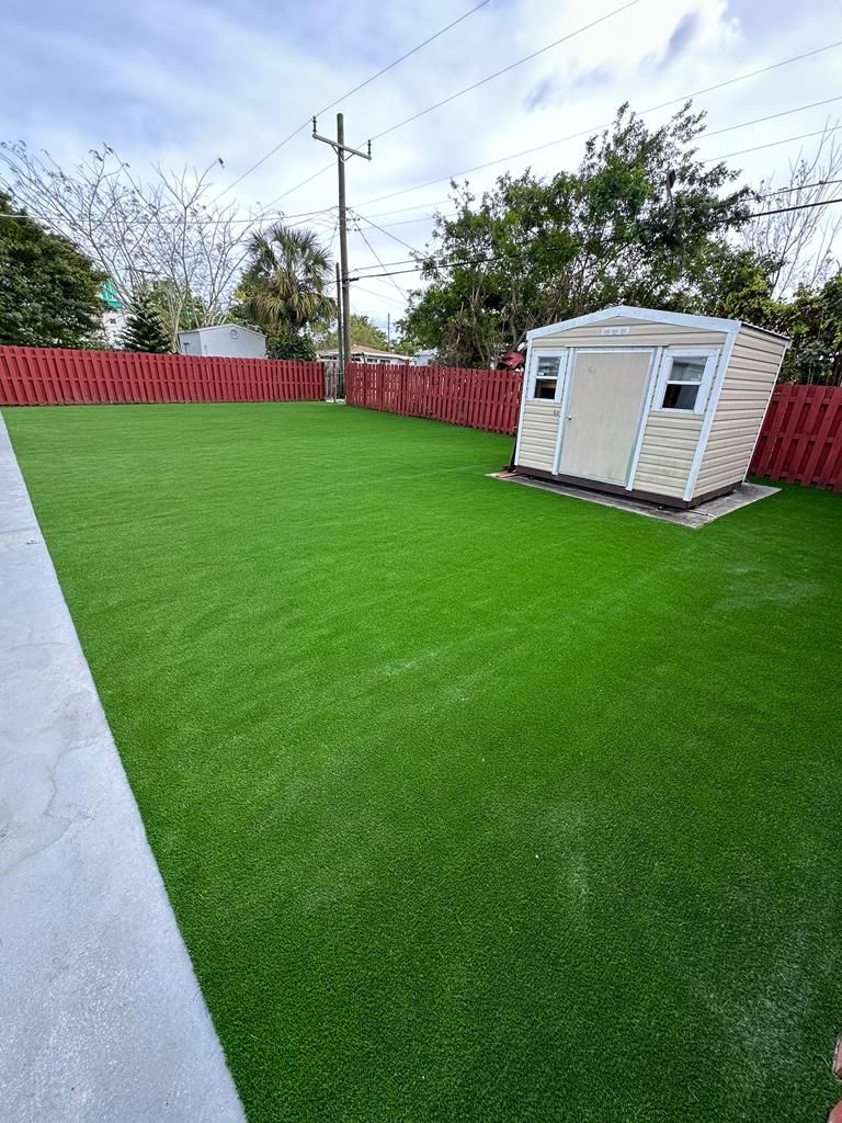 A shed is sitting on top of a lush green lawn in a backyard.