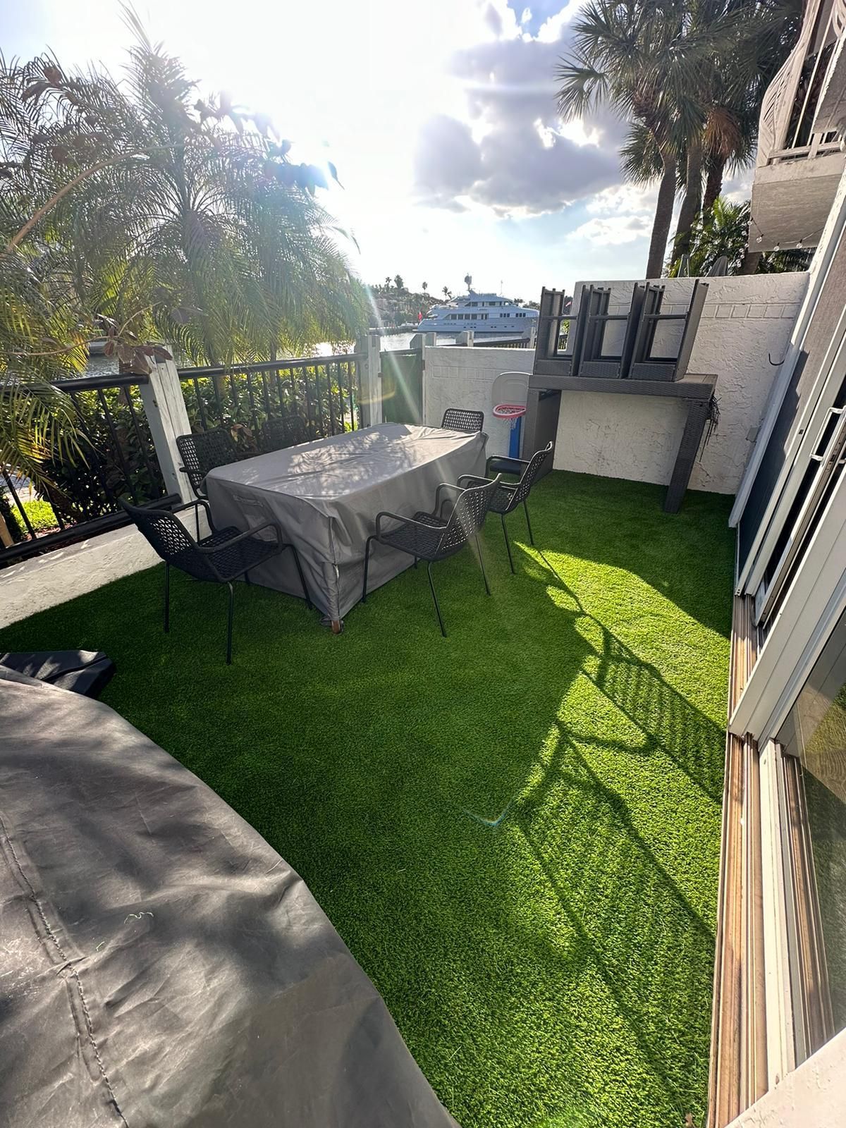 A patio with a table and chairs on top of a lush green lawn.