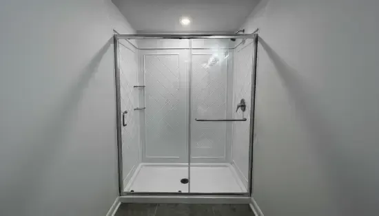 Modern bathroom with a glass-enclosed shower and white tiled walls, seen head-on.