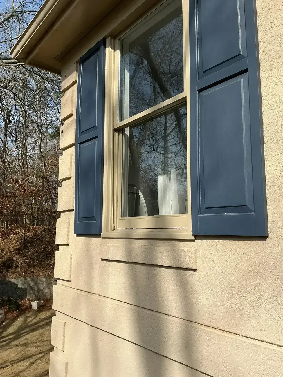 House exterior with blue shutters and a window on beige siding