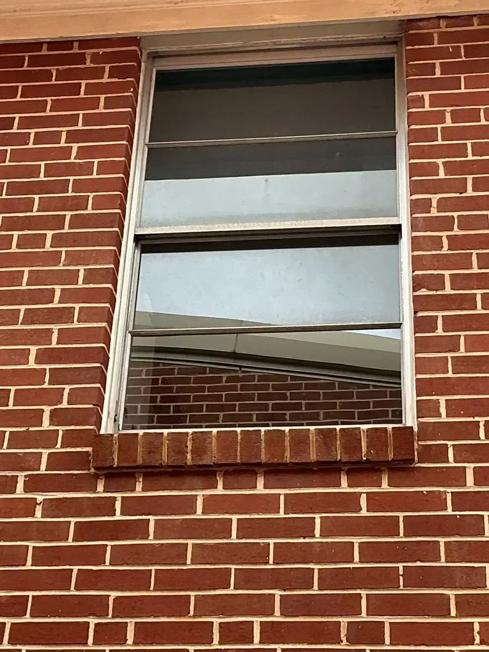 Brick building wall with a reflective window and partially open blinds