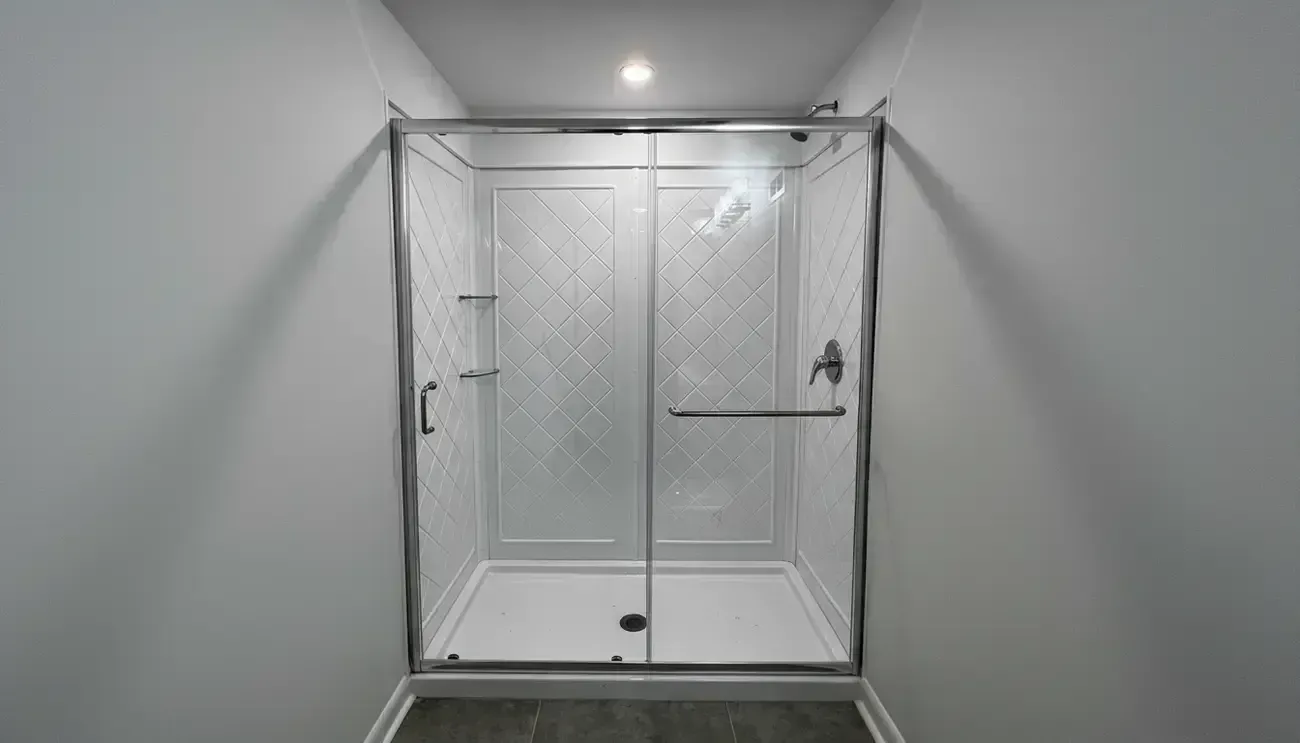 Clear glass shower enclosure with chrome trim and diagonal frosted panel inserts in a gray bathroom.