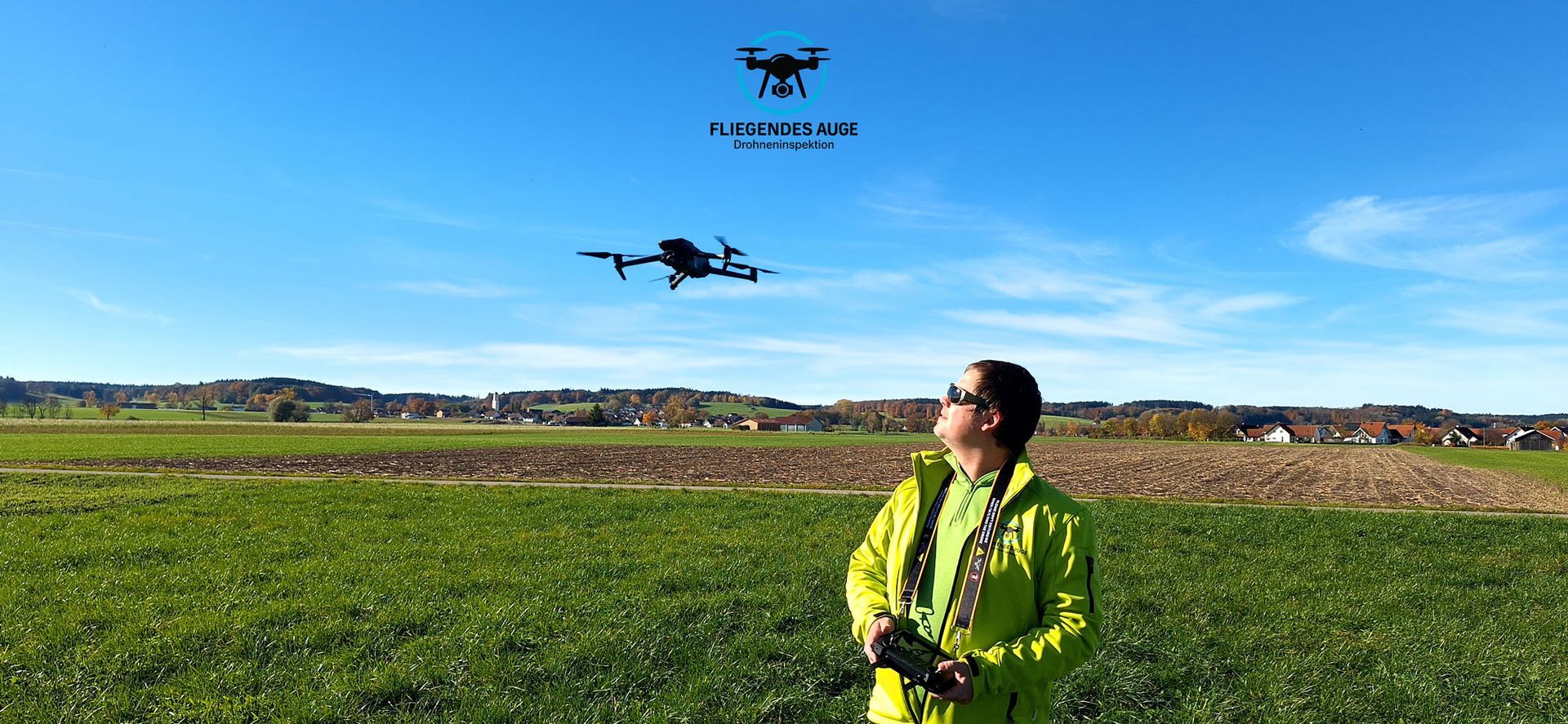 Drei Personen stehen auf einem Feld vor einem großen Gebäude.