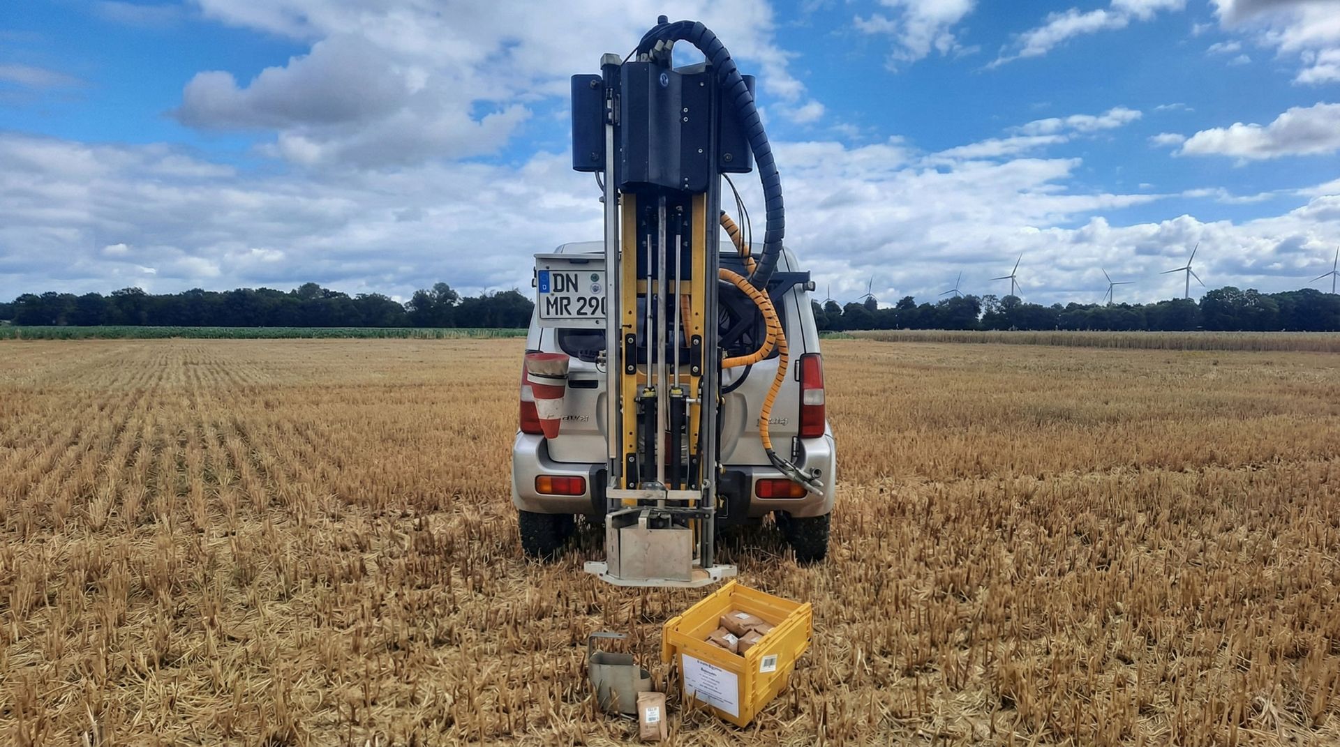 Ein Mähdrescher arbeitet bei Sonnenuntergang auf einem Maisfeld.