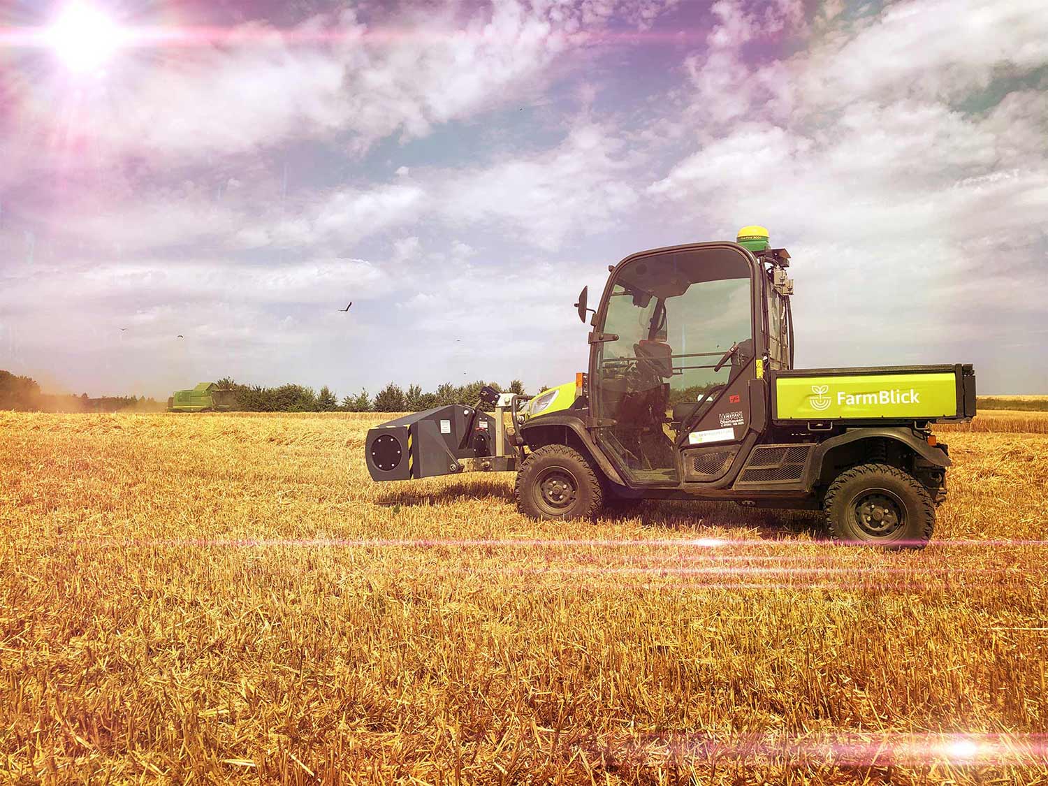 Ein Traktor fährt durch ein Weizenfeld.