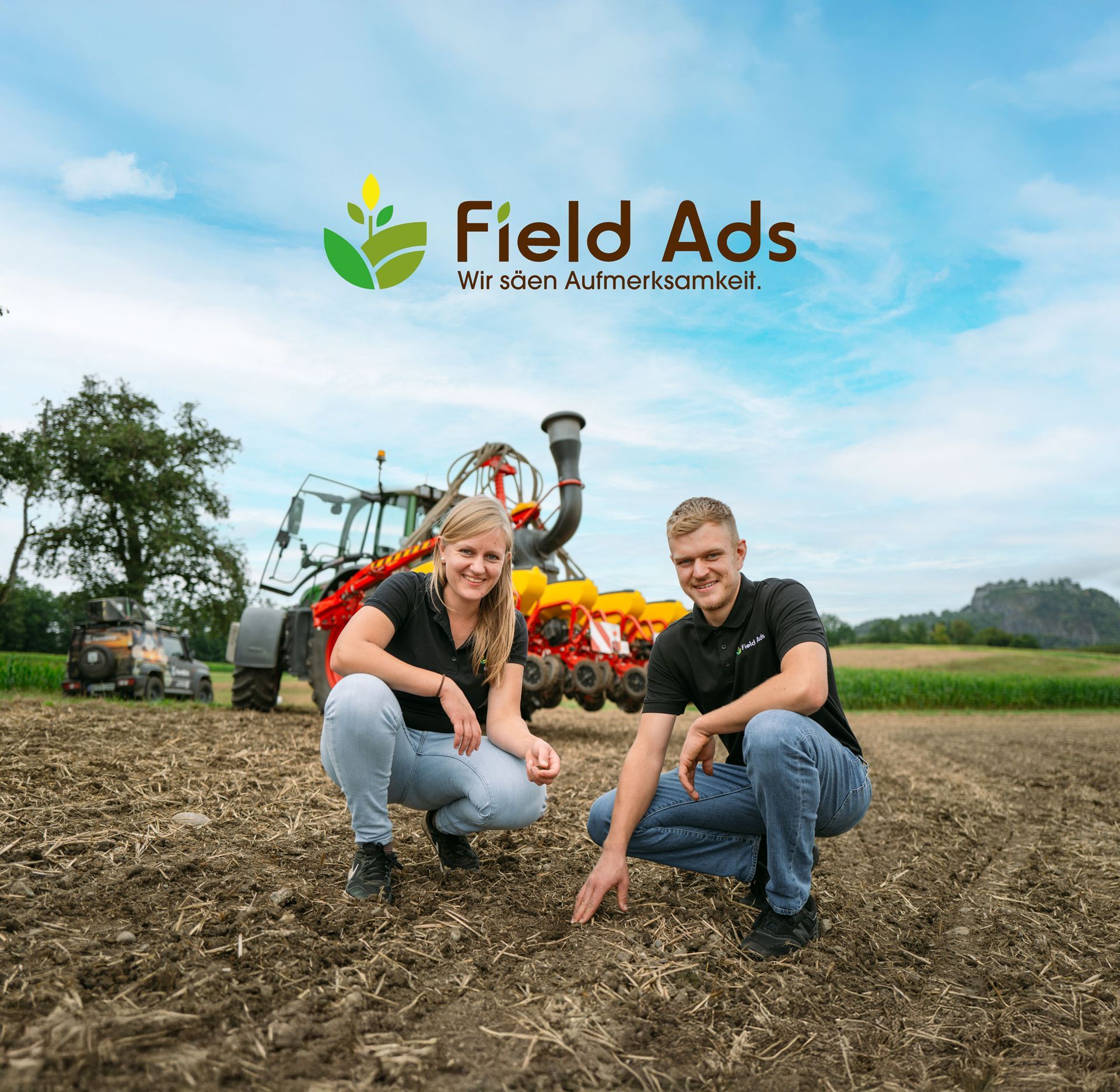 Ein grün-gelber Traktor besprüht ein Grasfeld.