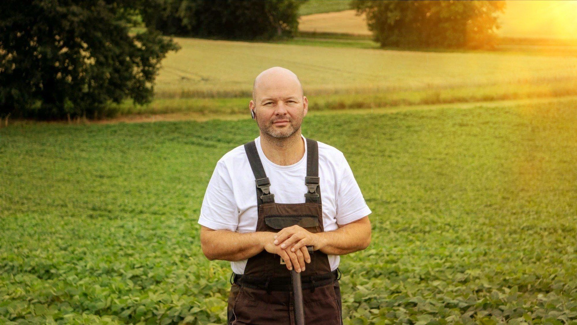 Ein Mann steht mit einer Schaufel in der Hand auf einem Feld.