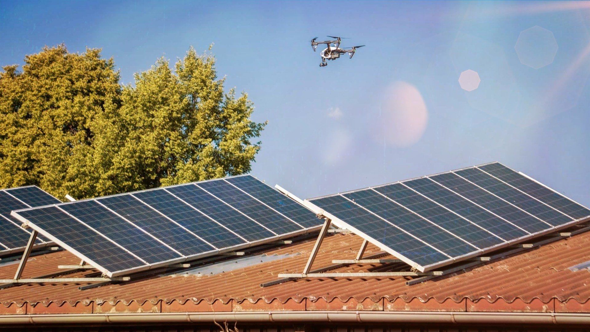 Eine Drohne fliegt über ein Dach mit Solarmodulen.