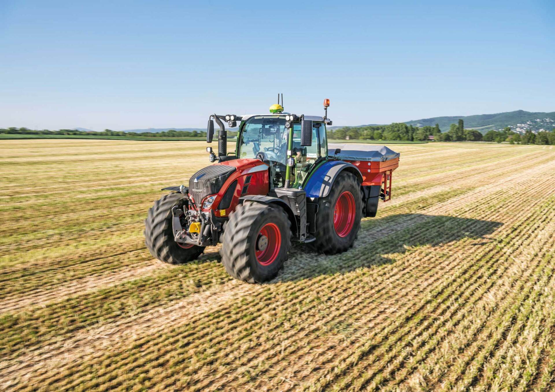 Ein Traktor mit einem Anhänger fährt durch ein Feld.