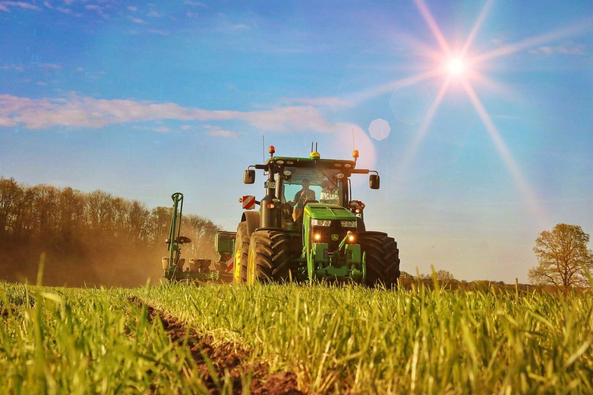 An einem sonnigen Tag pflügt ein grüner Traktor ein Feld.
